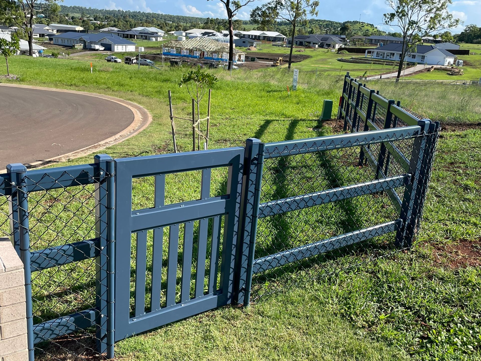 A blue fence is sitting in the middle of a grassy field.