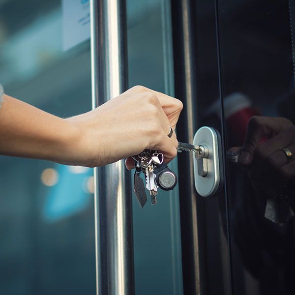 person putting key in door lock