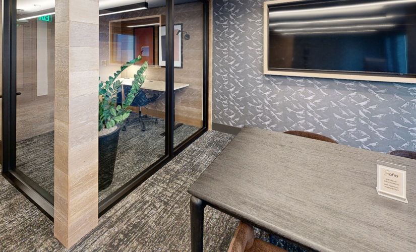Leasing office area with glass partitions, a conference table, and a wall-mounted screen at Sofia.