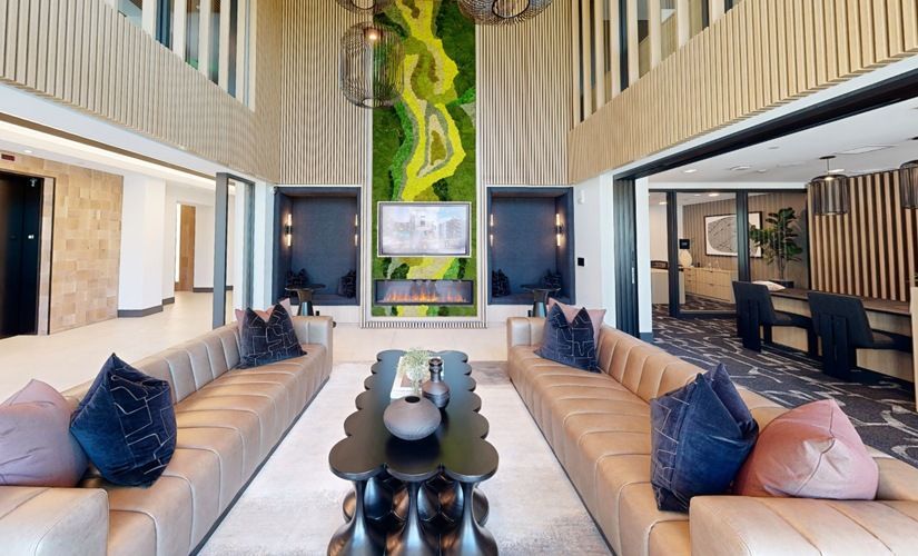 Indoor resident lounge with tan sectional sofas, dark coffee tables, and a vertical moss wall at Sofia, offers pet-friendly apartments in Santa Clara.
