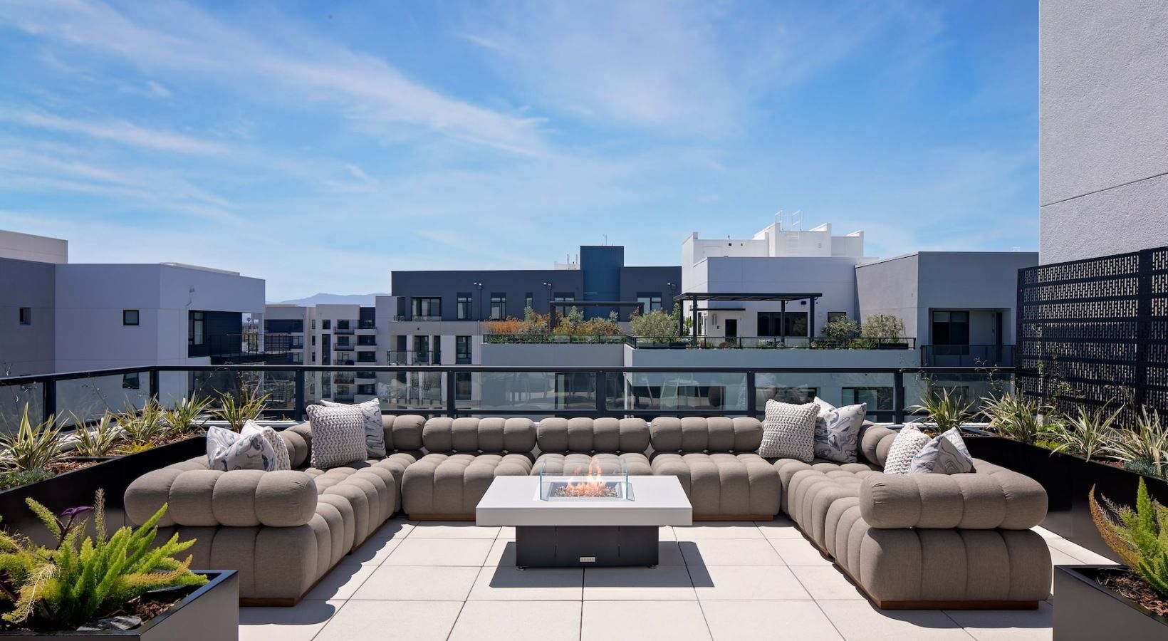 Rooftop lounge with beige sectional seating and a central fire pit at Sofia, offers Santa Clara apartments for rent in CA.