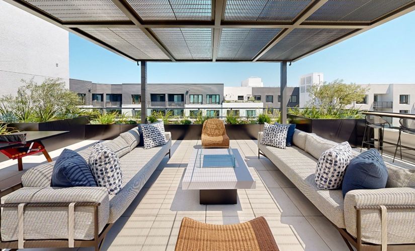 Outdoor rooftop lounge with sectional seating, cushions, and a shaded canopy at Sofia, offers pet-friendly apartments in Santa Clara.