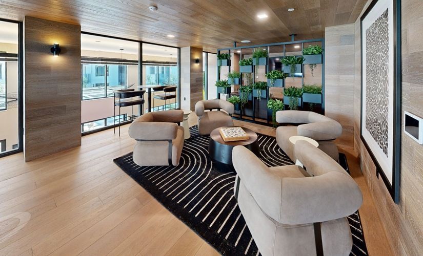 Modern community lounge with beige seating, a rug, and a plant wall at Sofia, offers pet-friendly apartments in Santa Clara.