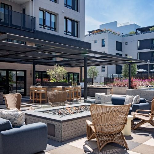 Outdoor community lounge on a rooftop terrace with seating and a fire pit under a pergola at Sofia, offers pet-friendly apartments in Santa Clara.