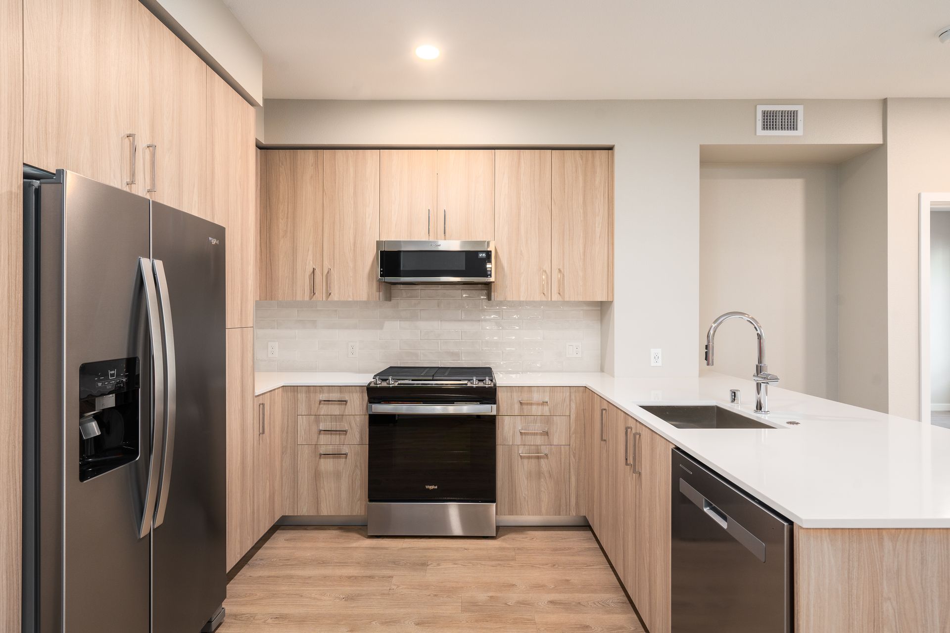 Modern kitchen with light wood cabinets, stainless steel appliances, and white countertops at Sofia, offers apartments in Santa Clara.
