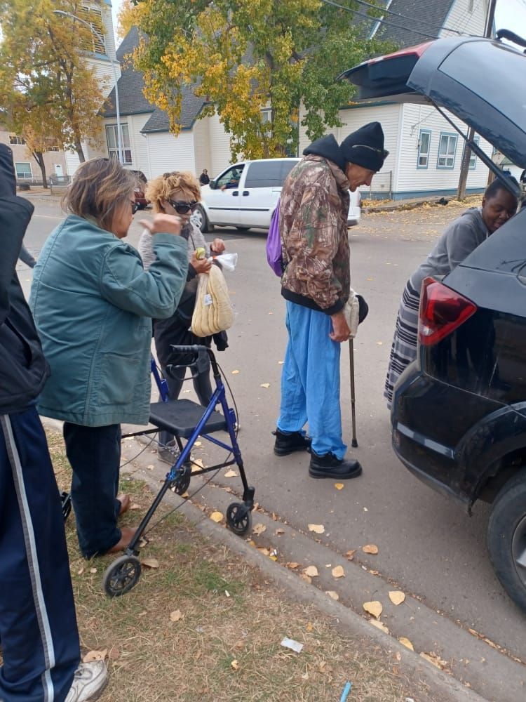 a group of people are standing next to a car on the side of the road .