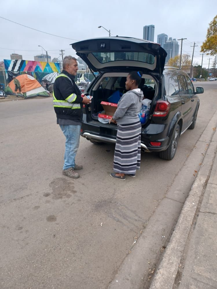 a man and a woman are standing next to a car with the trunk open .