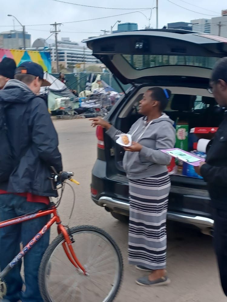 a woman standing in front of a car holding a plate of food