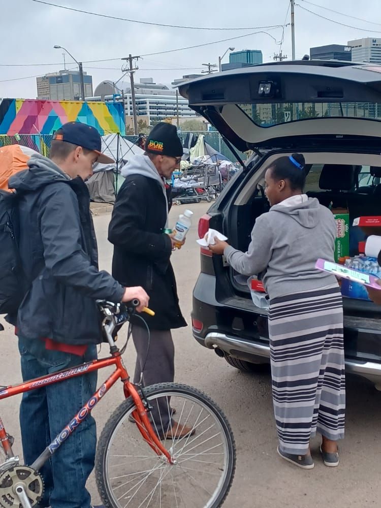 a group of people standing next to a bicycle and a car