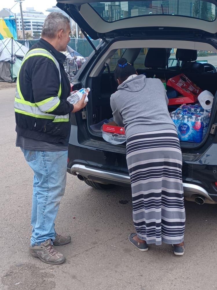 a man and a woman are looking into the back of a car .