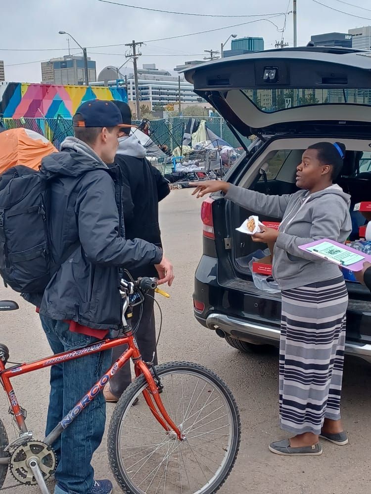 a man and a woman are standing next to a bicycle and a car .