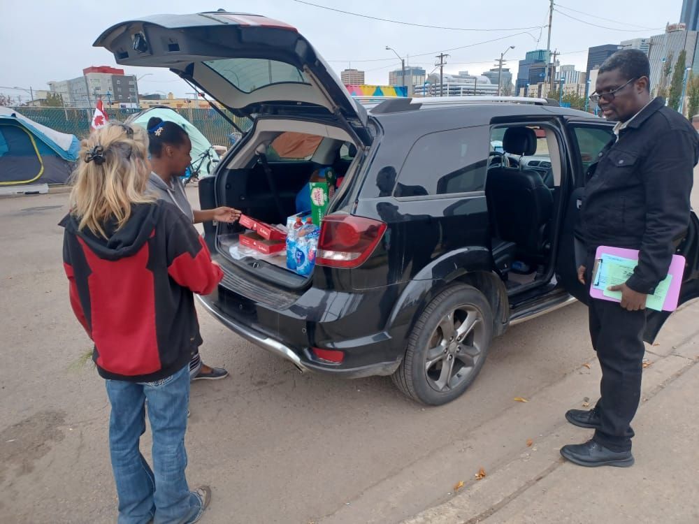two people are standing next to a black suv with the trunk open