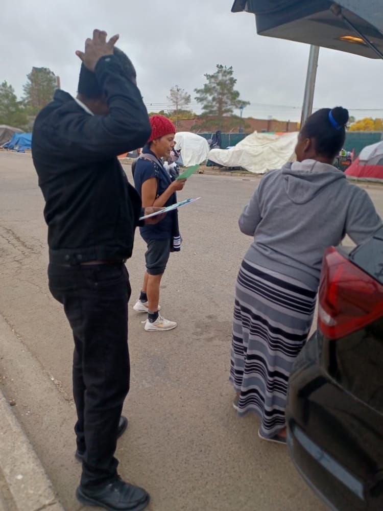 a man and a woman are standing next to a car in a parking lot .