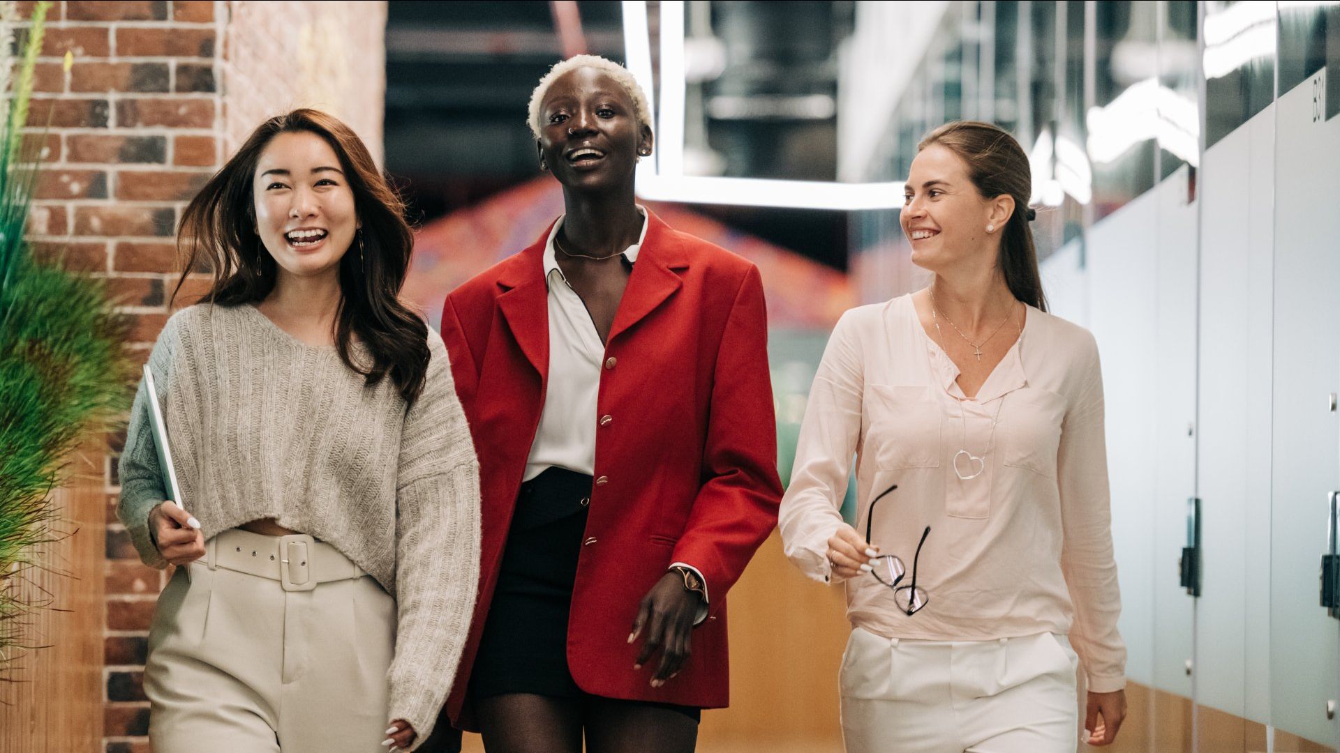 three women are walking down a hallway together .
