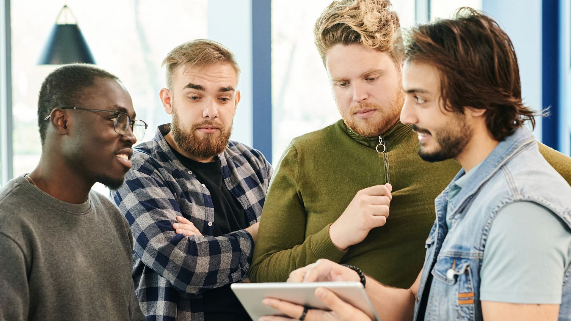 a group of men are looking at a tablet together .