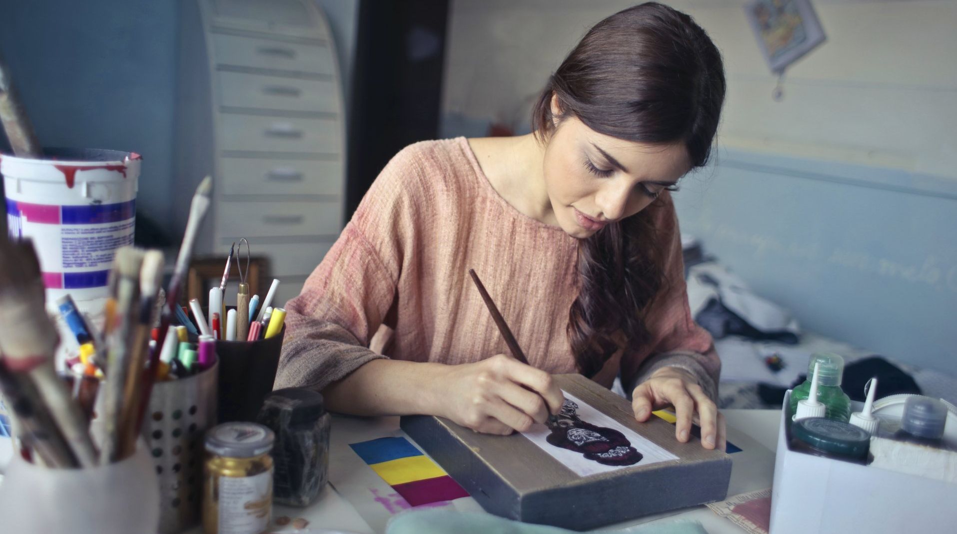 a woman is sitting at a table painting a picture with a brush .