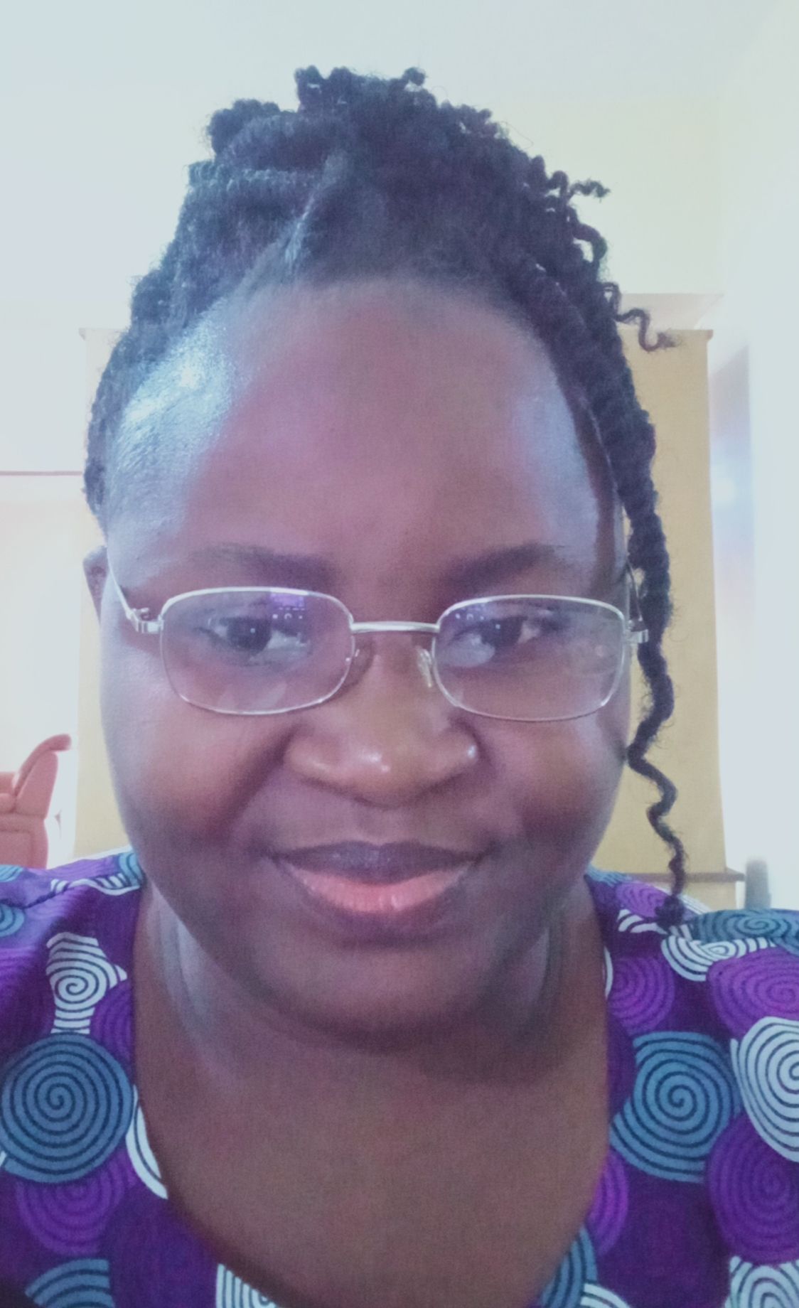 Person wearing glasses and a purple patterned top, smiling in a close-up selfie.
