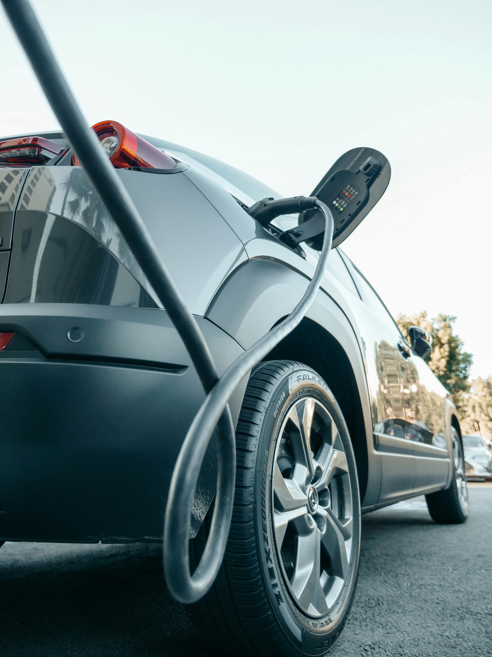 A close up of an electric car being charged on a street.