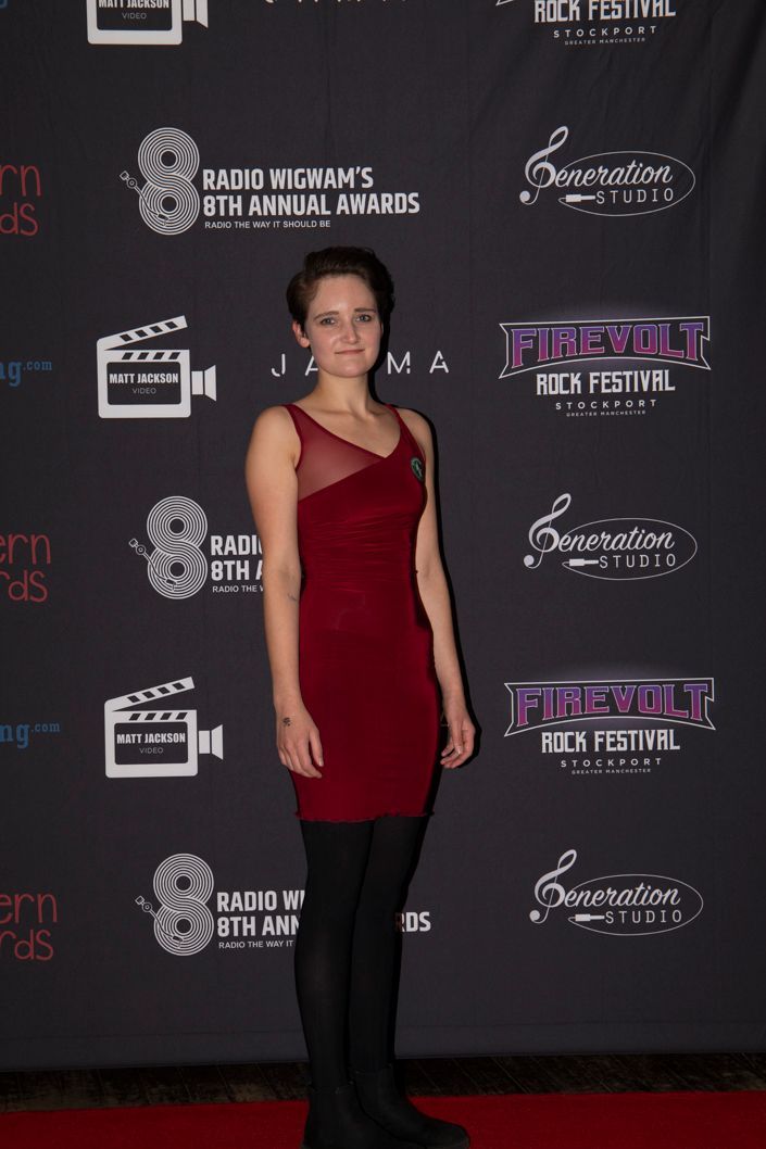 Nina Condron in red dress and black tights at the Radio wigwam Awards show on the red carpet