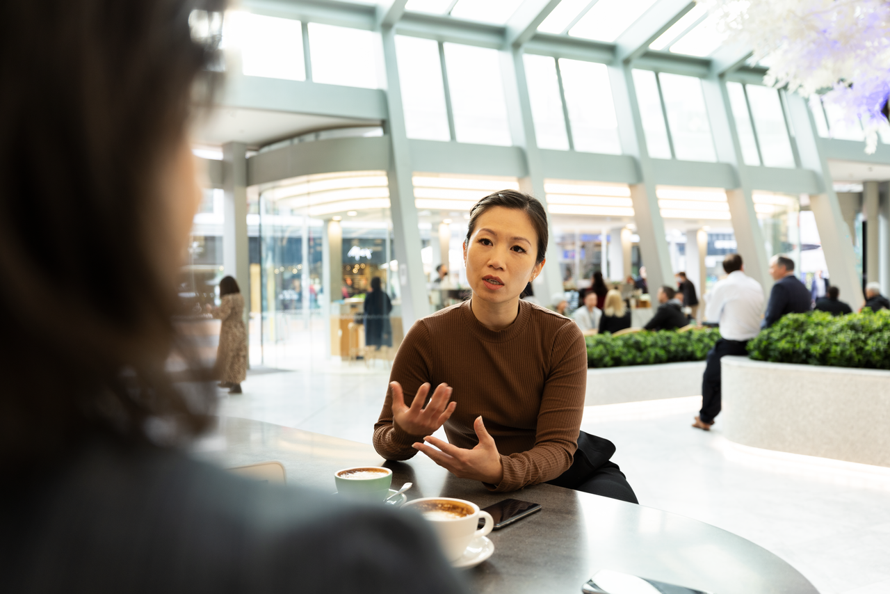 A woman is sitting at a table talking to another person.