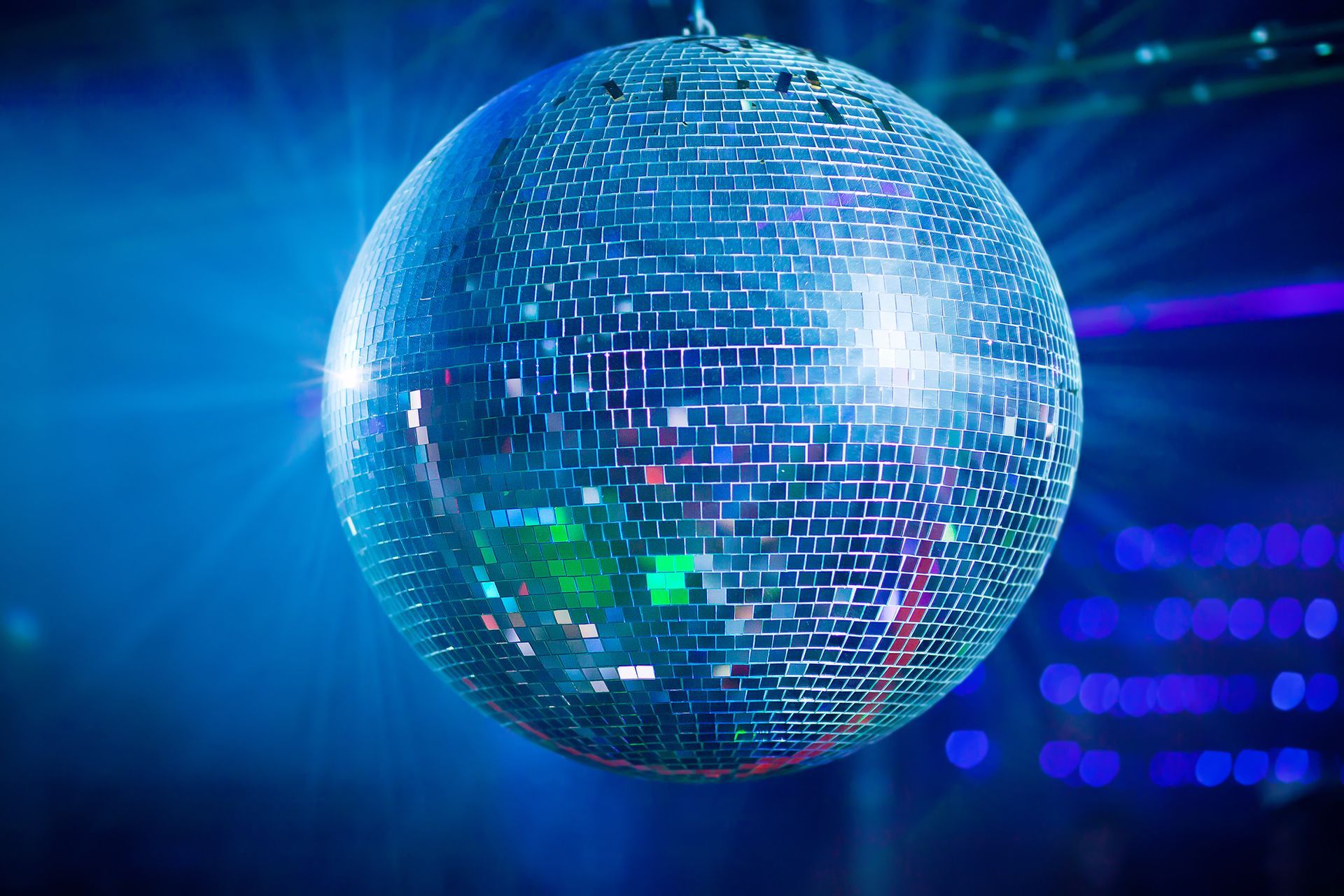 Bola de discoteca brillante que refleja luz azul y verde en un entorno oscuro.