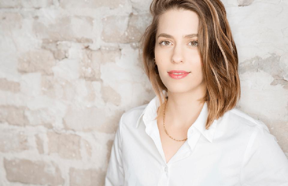 mulher jovem, de cabelos claros e curtos, posa para foto com camisa social branca