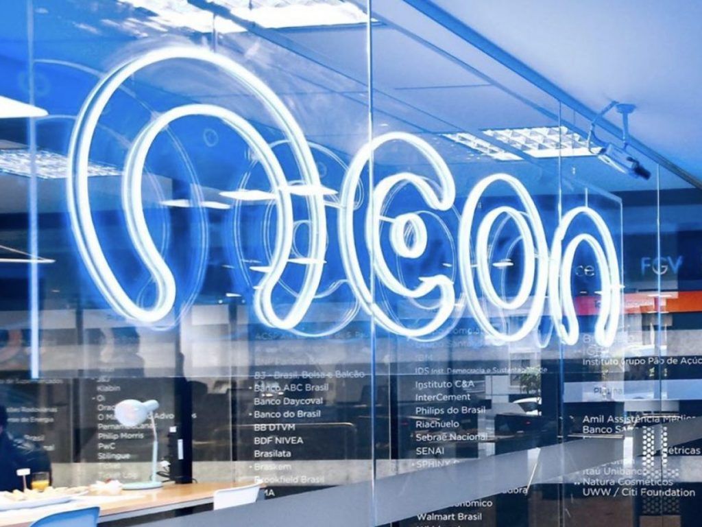 foto da sede do banco neon. mostra uma janela com um letreiro em neon azul com o nome do banco escrito