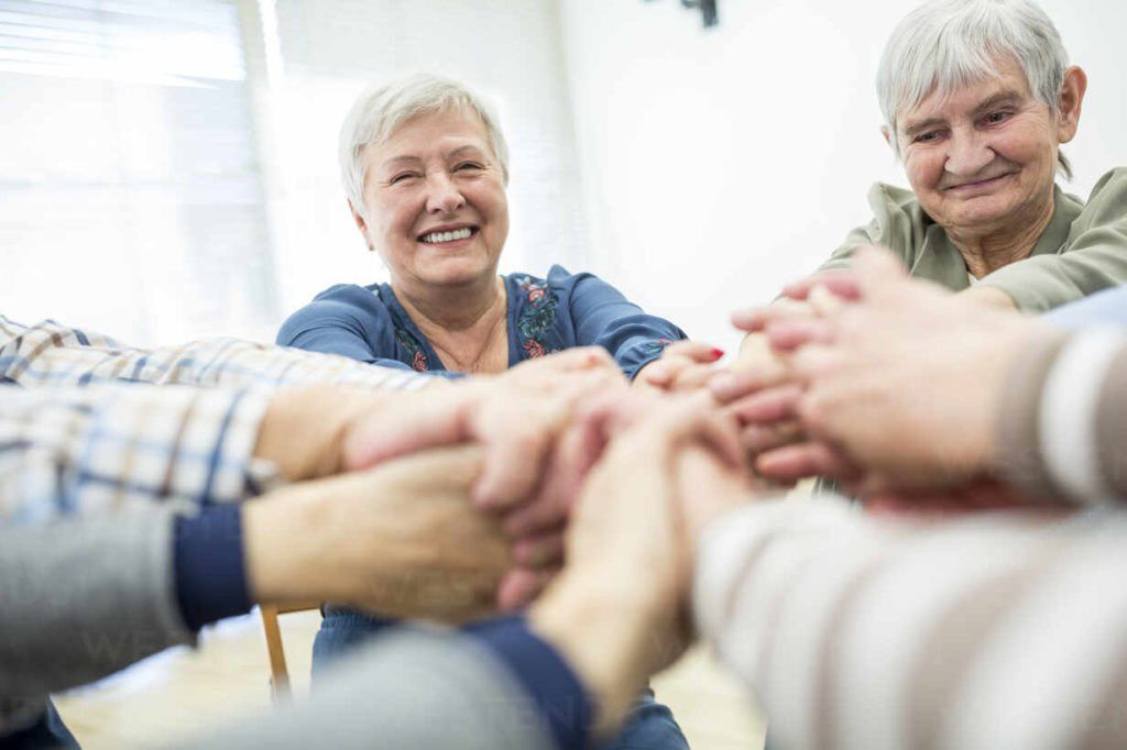 maturis dão às mãos em sinal de união. sorriem mostrando satisfação