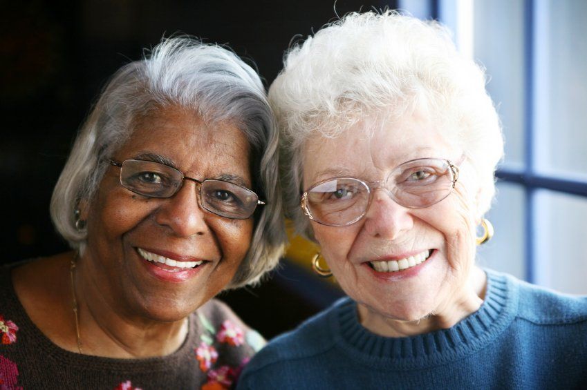 duas mulheres maduras sorriem juntas, elas estão com as cabeças recostas