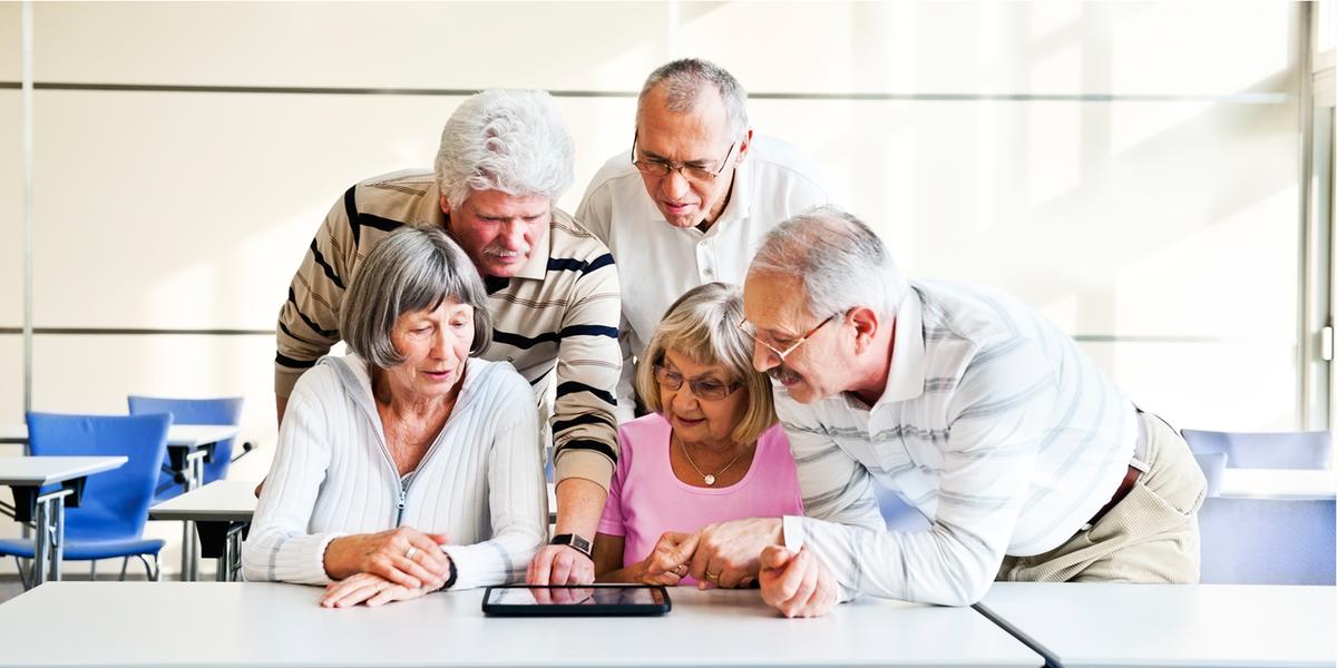 maturis conversam atrás de uma mesa olhando para um tablet
