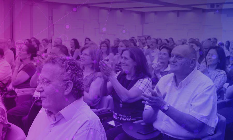 público no MaturiFest, o público sorri e bate palmas enquanto assistem uma palestra