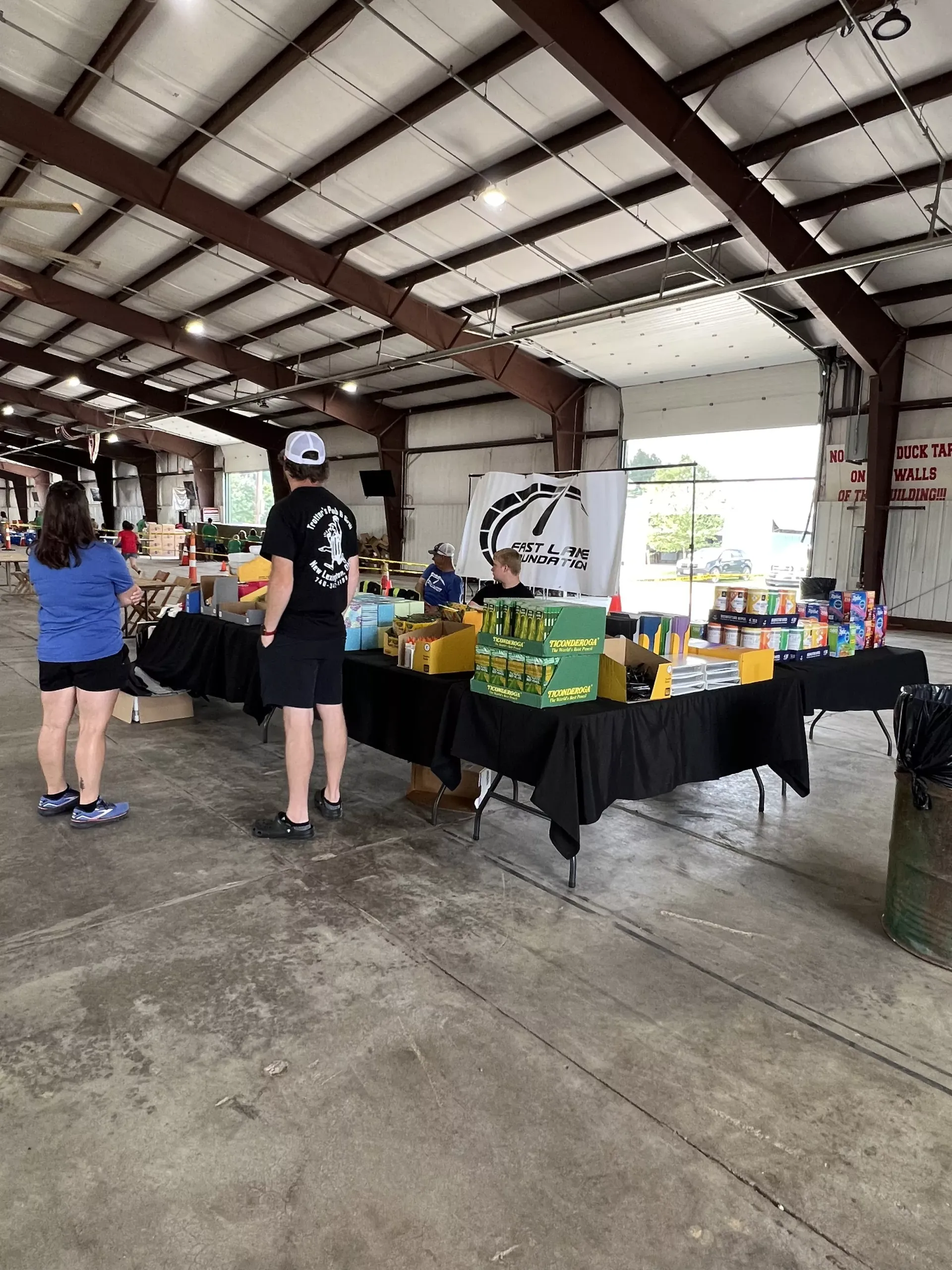 Vendor tables with colorful items in a large open-air pavilion, with a few people browsing.