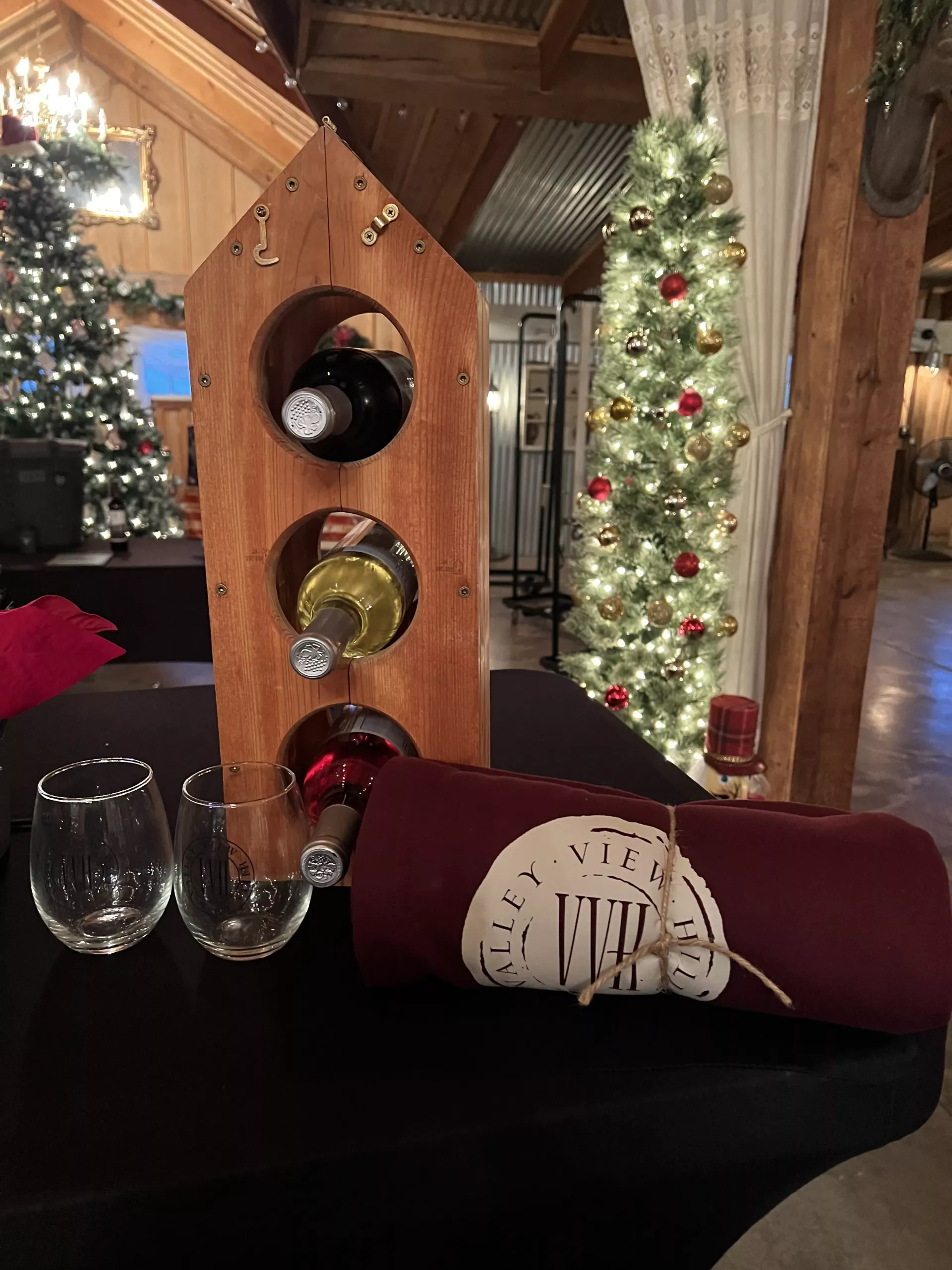 Holiday table display with wine rack, glasses, napkins, and Christmas trees in a cozy cabin lounge