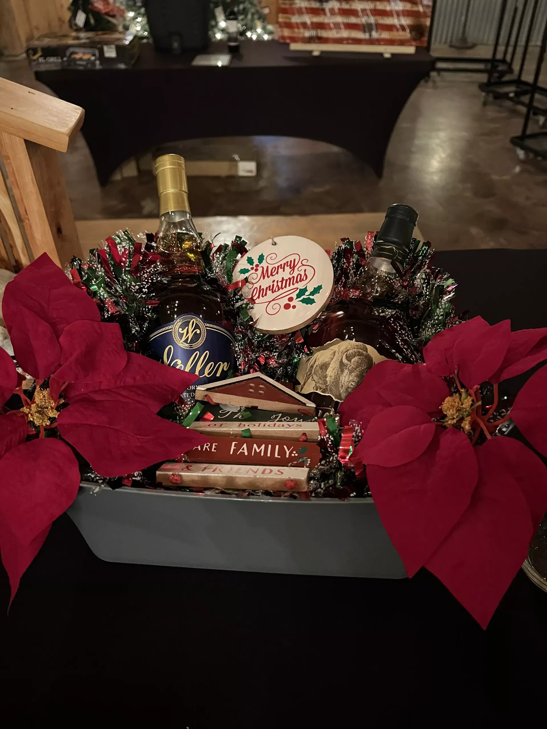 Festive gift basket with poinsettias, tinsel, and holiday treats on a dark table