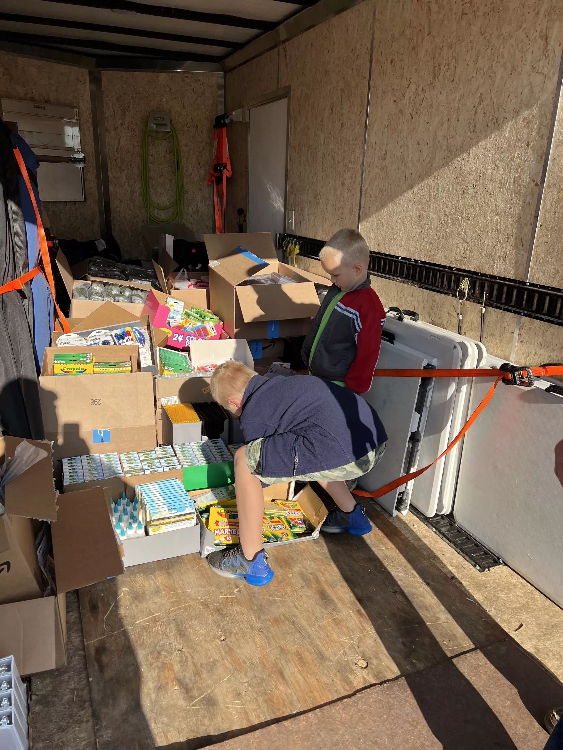 Two people sorting donated goods in a truck with cardboard boxes and packed supplies