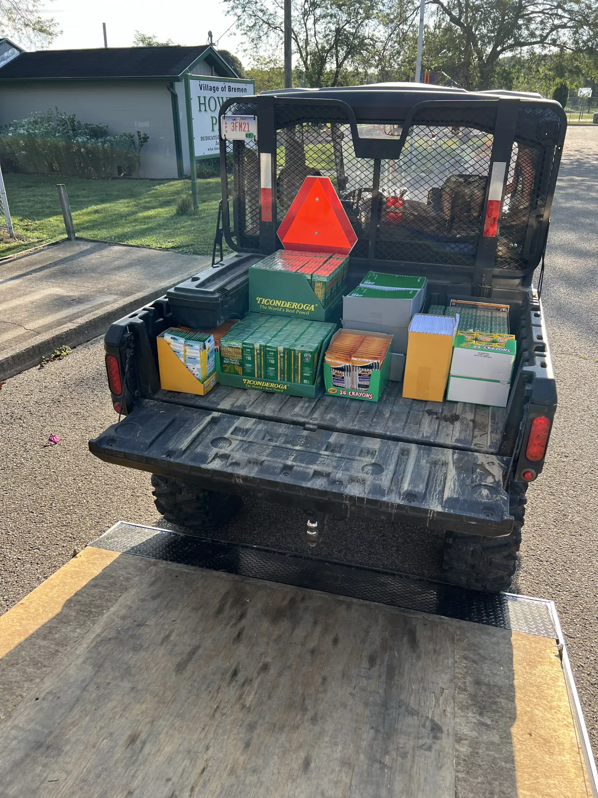 Pickup truck bed loaded with wrapped gifts and boxes, including a red caution triangle, parked on a driveway.