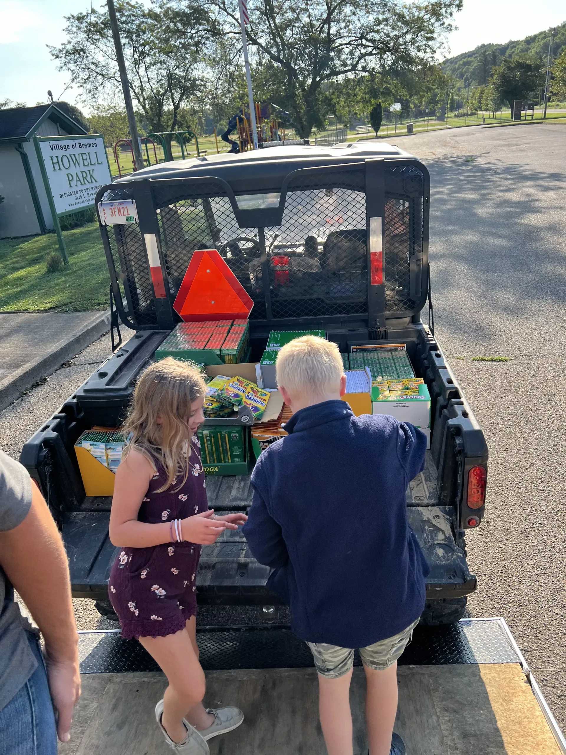 Two people loading items into the back of a pickup truck at a park entrance