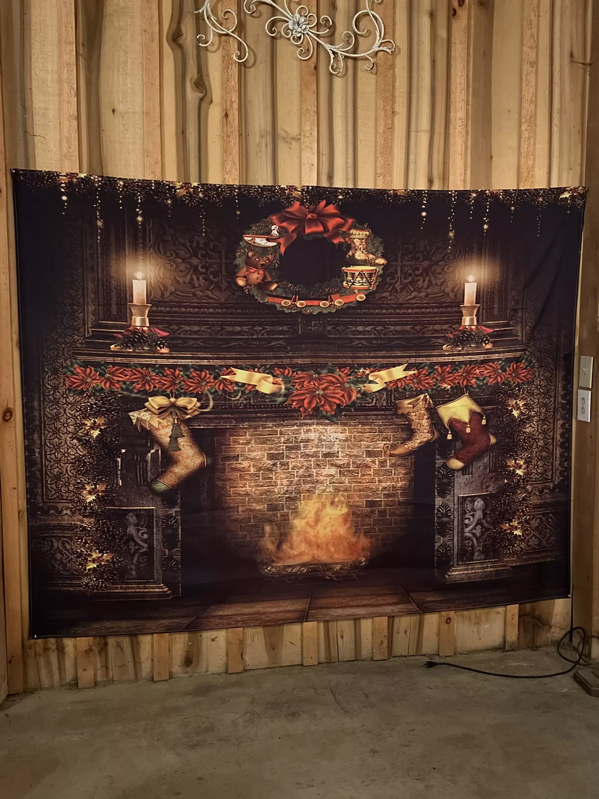 Festive fireplace mural with candles, wreath, and garland against a wood-paneled wall