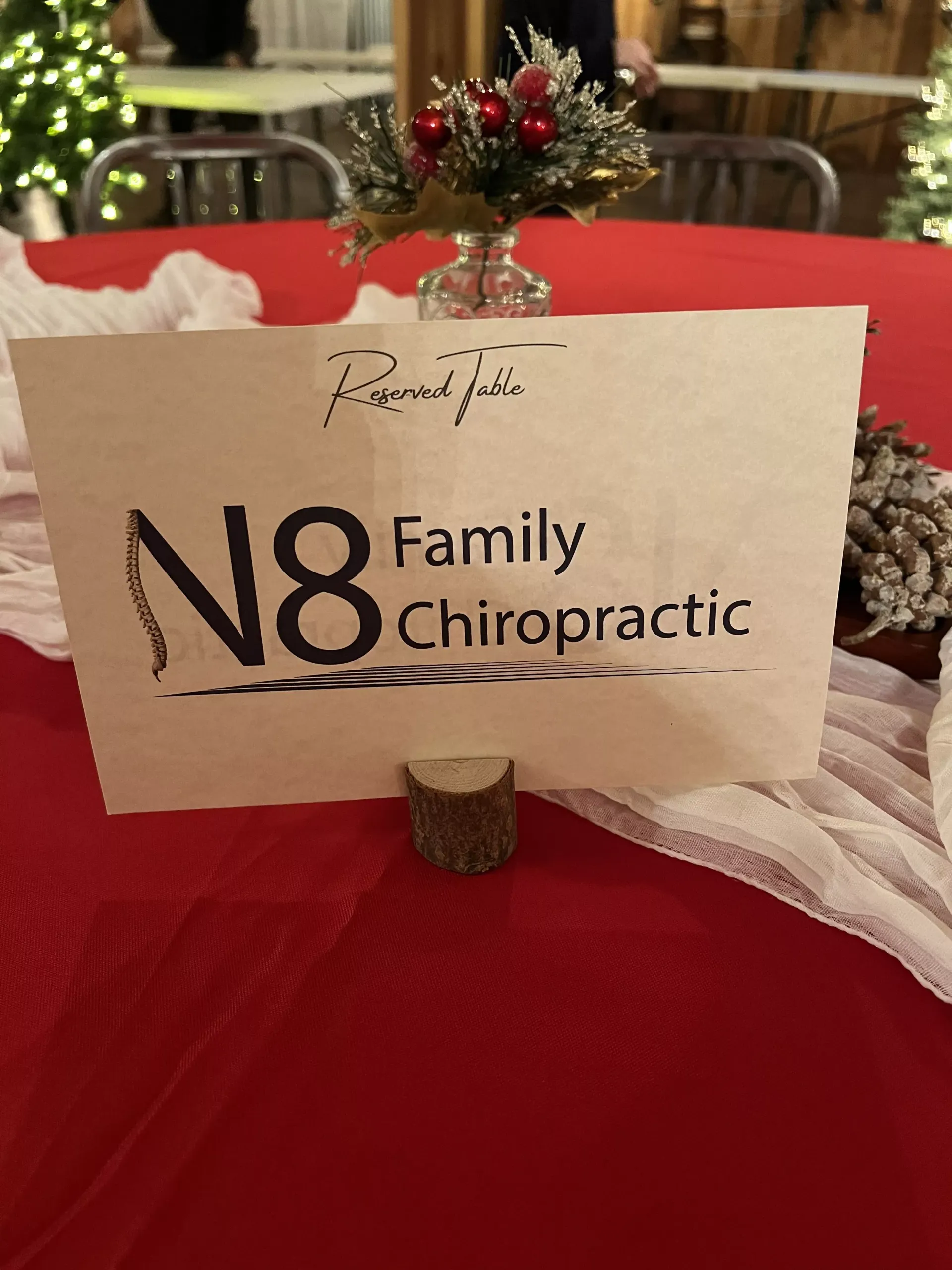 N8 Family Chiropractic table card on a red tablecloth with a small floral centerpiece