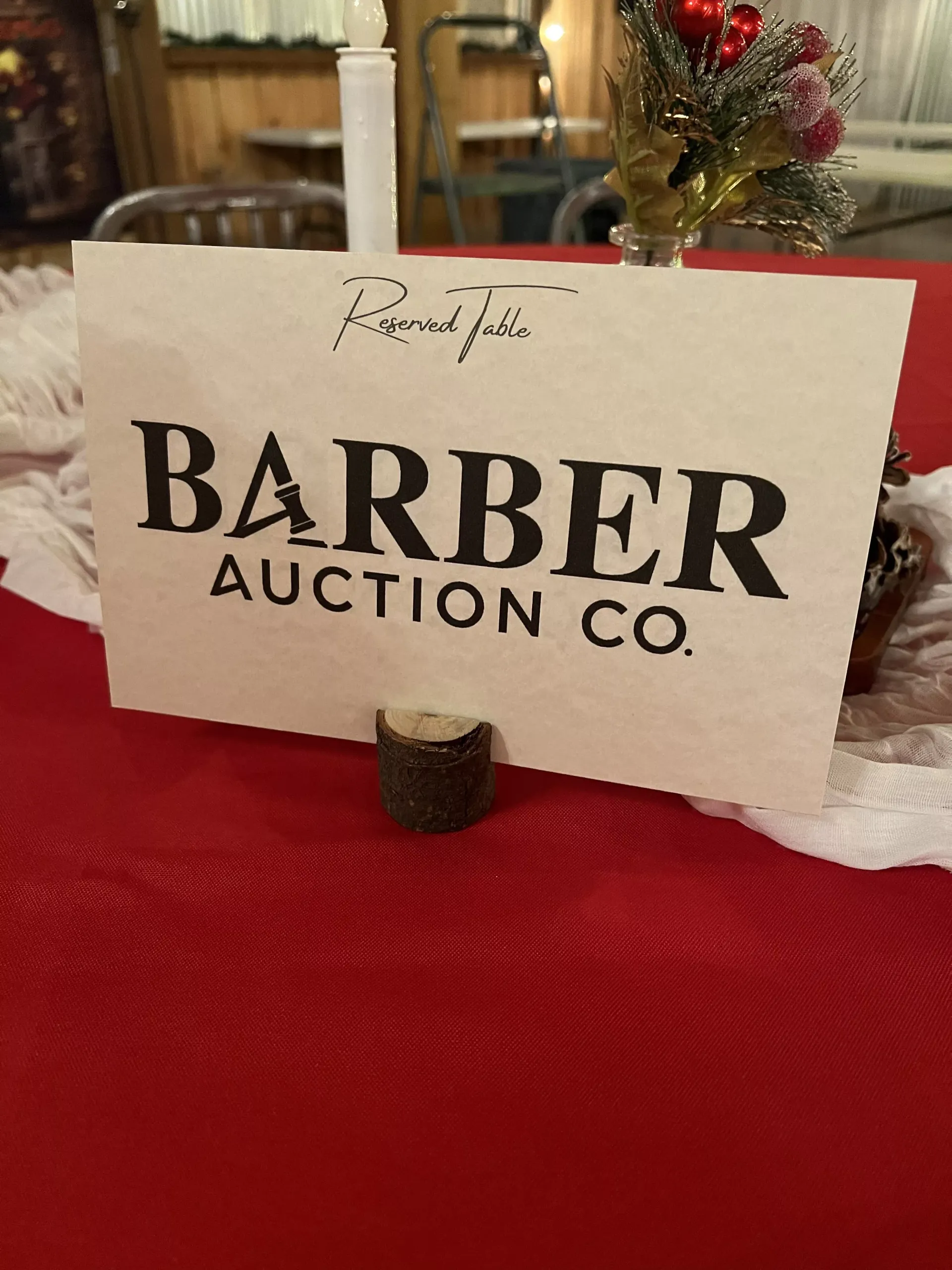 Barber Auction Co. sign on a red tablecloth at an indoor table setting