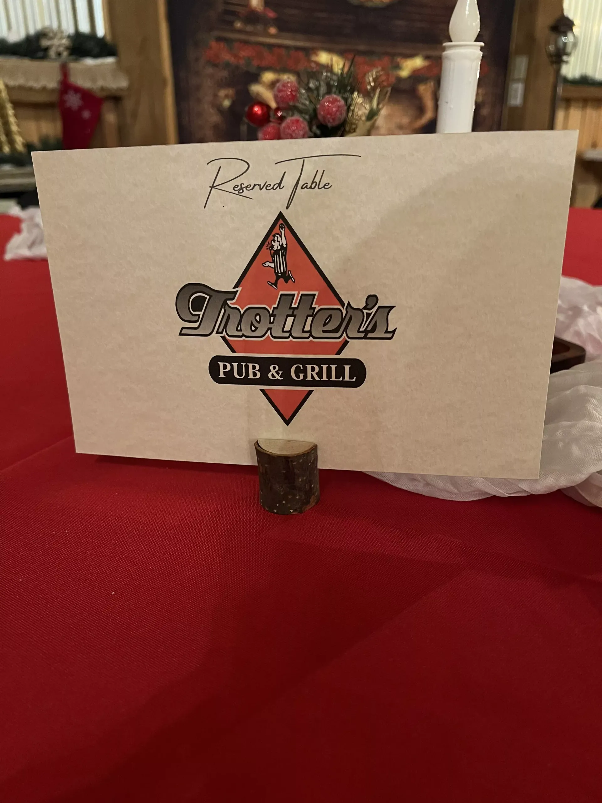 Restaurant logo on a napkin holder on a red tablecloth in a dimly lit dining room