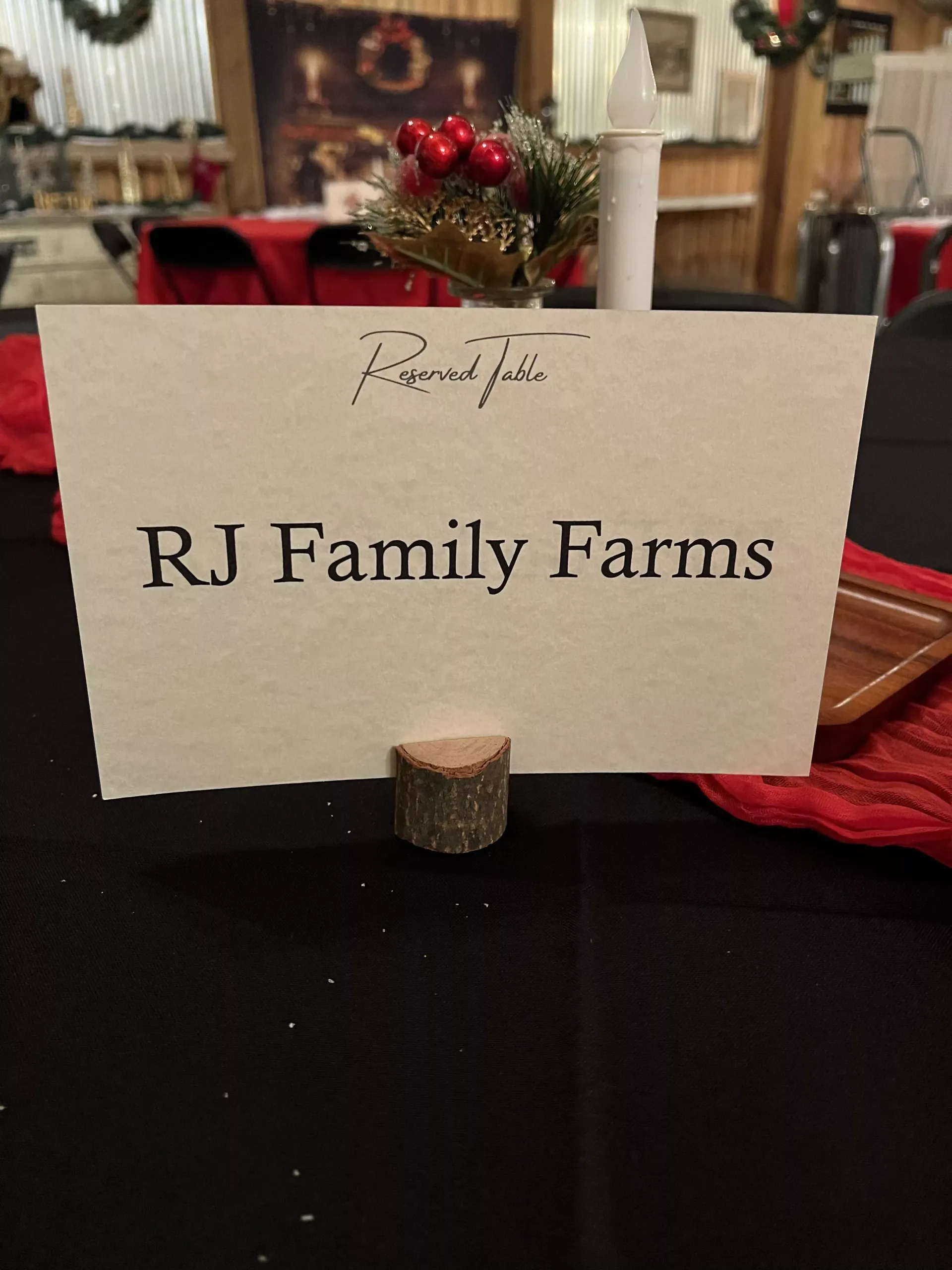 RJ Family Farms table sign on a black tablecloth with red and gold decor in the background