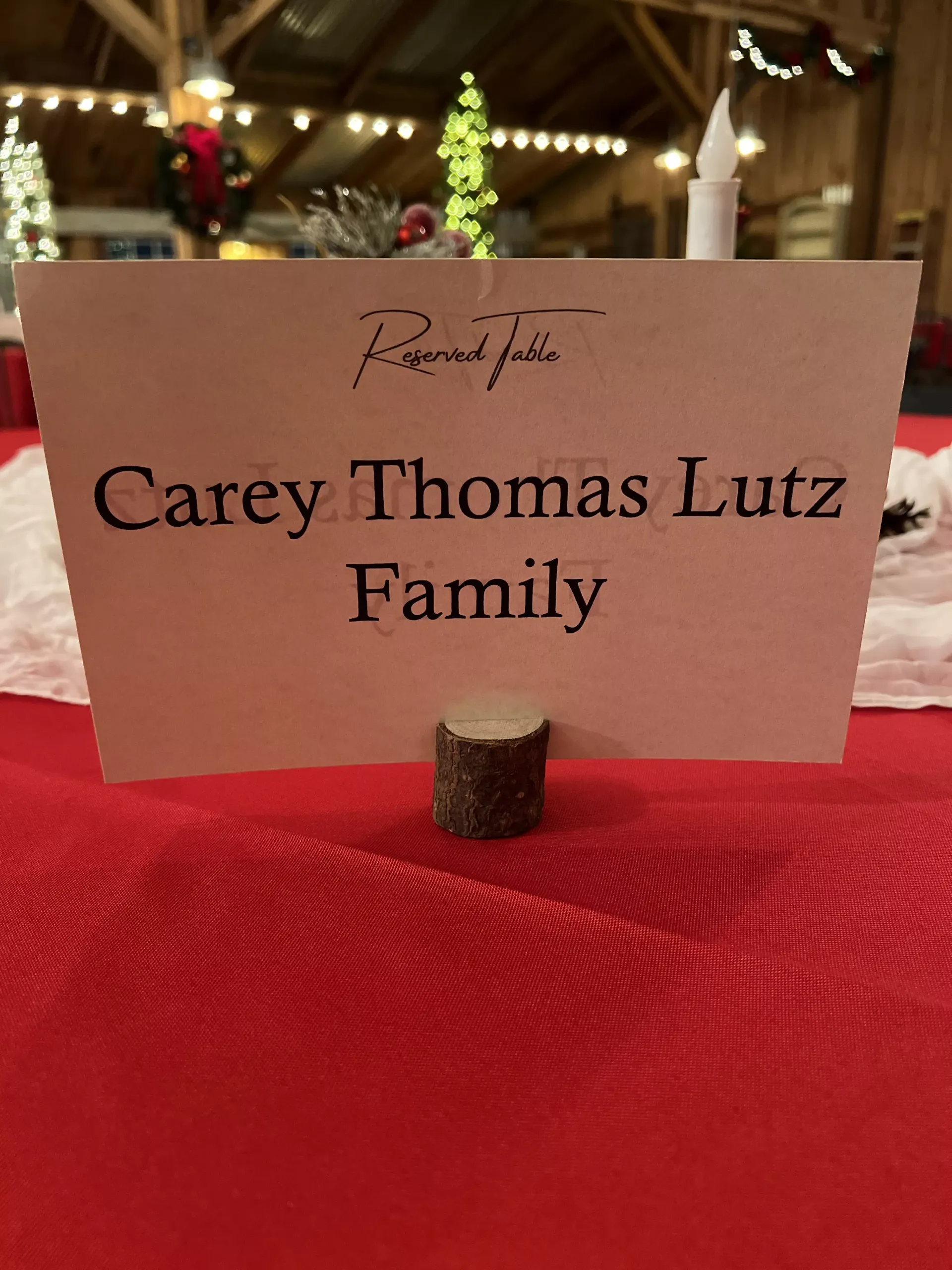 Table card reading “Carey Thomas Lutz Family” on a red cloth-covered table at an indoor event.