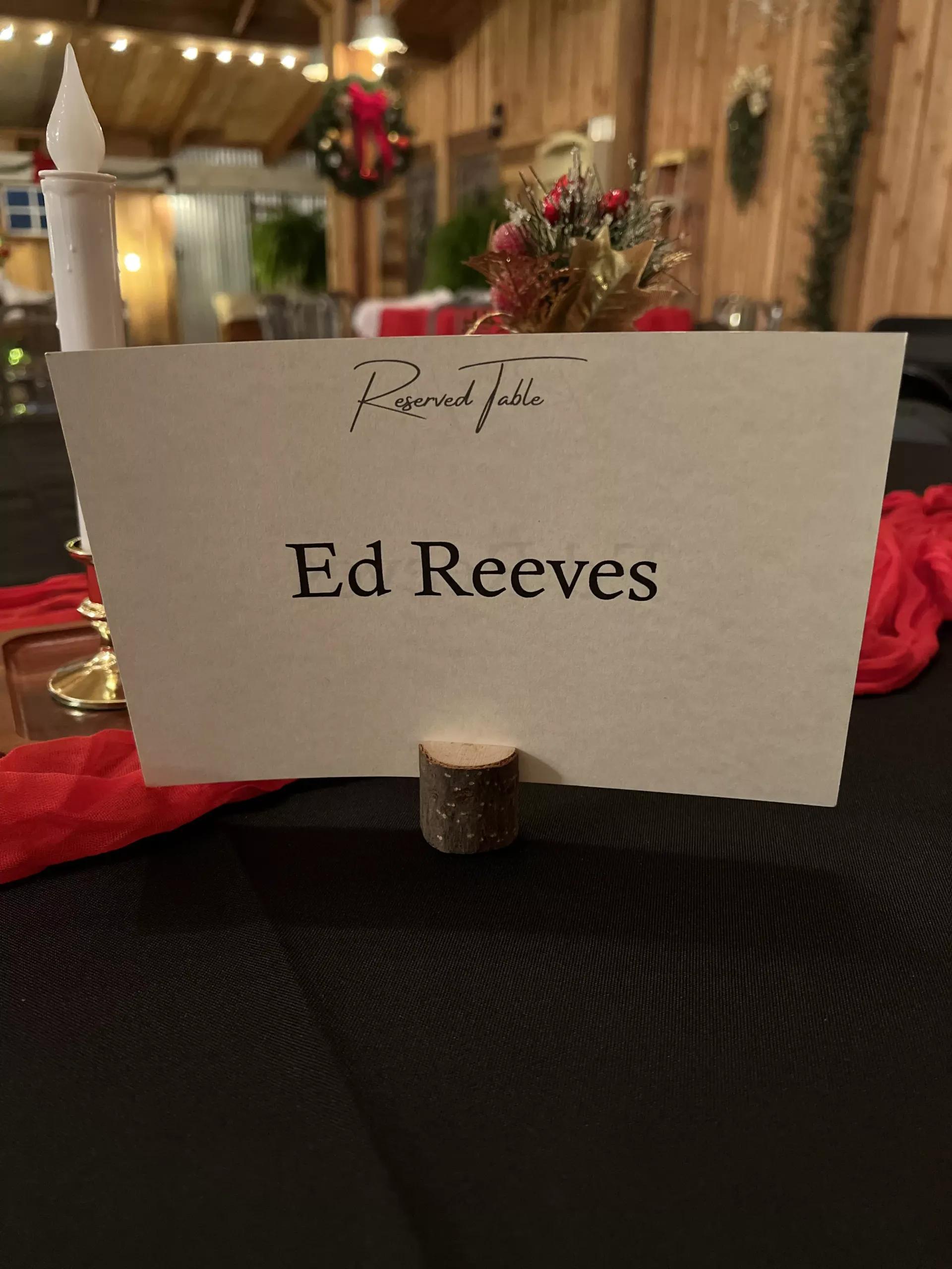 Place card reading “Ed Reeves” on a table in a warmly lit, decorated venue.