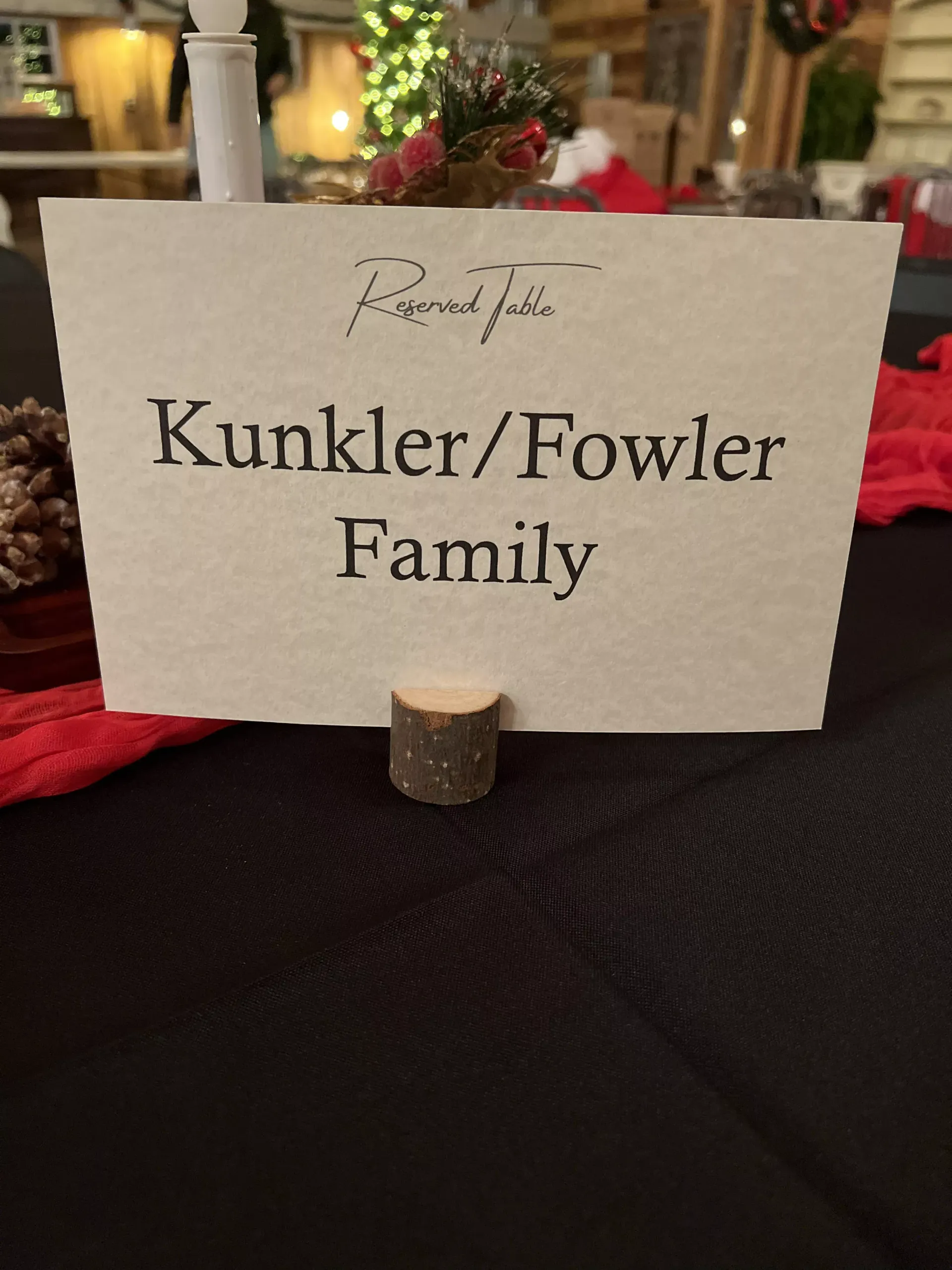 Table card reading “Kunkler/Fowler Family” on a black tablecloth, with red and gold decor in the background