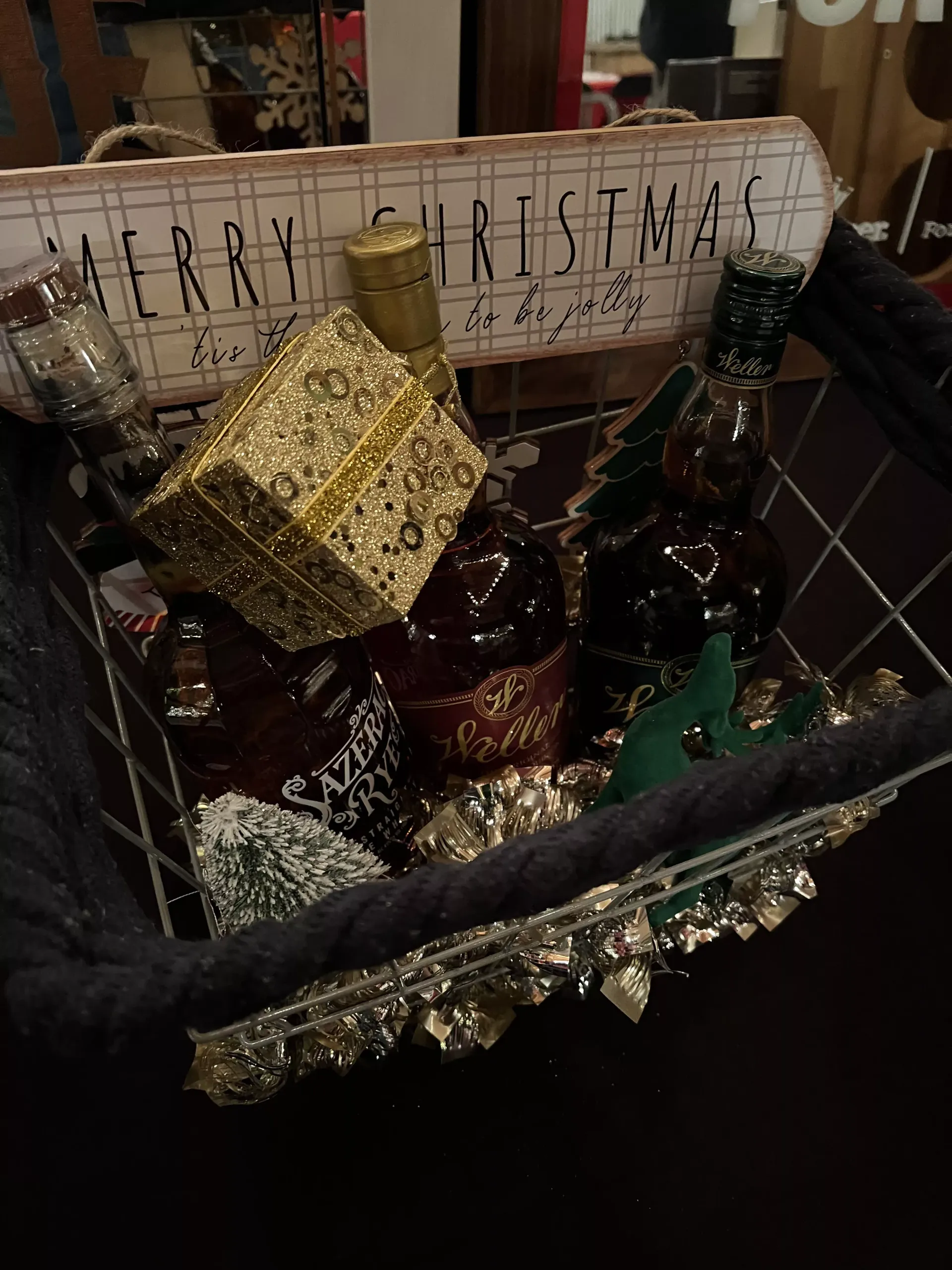 Decorated Christmas basket with gold gift boxes, bottles, and a “Merry Christmas” sign
