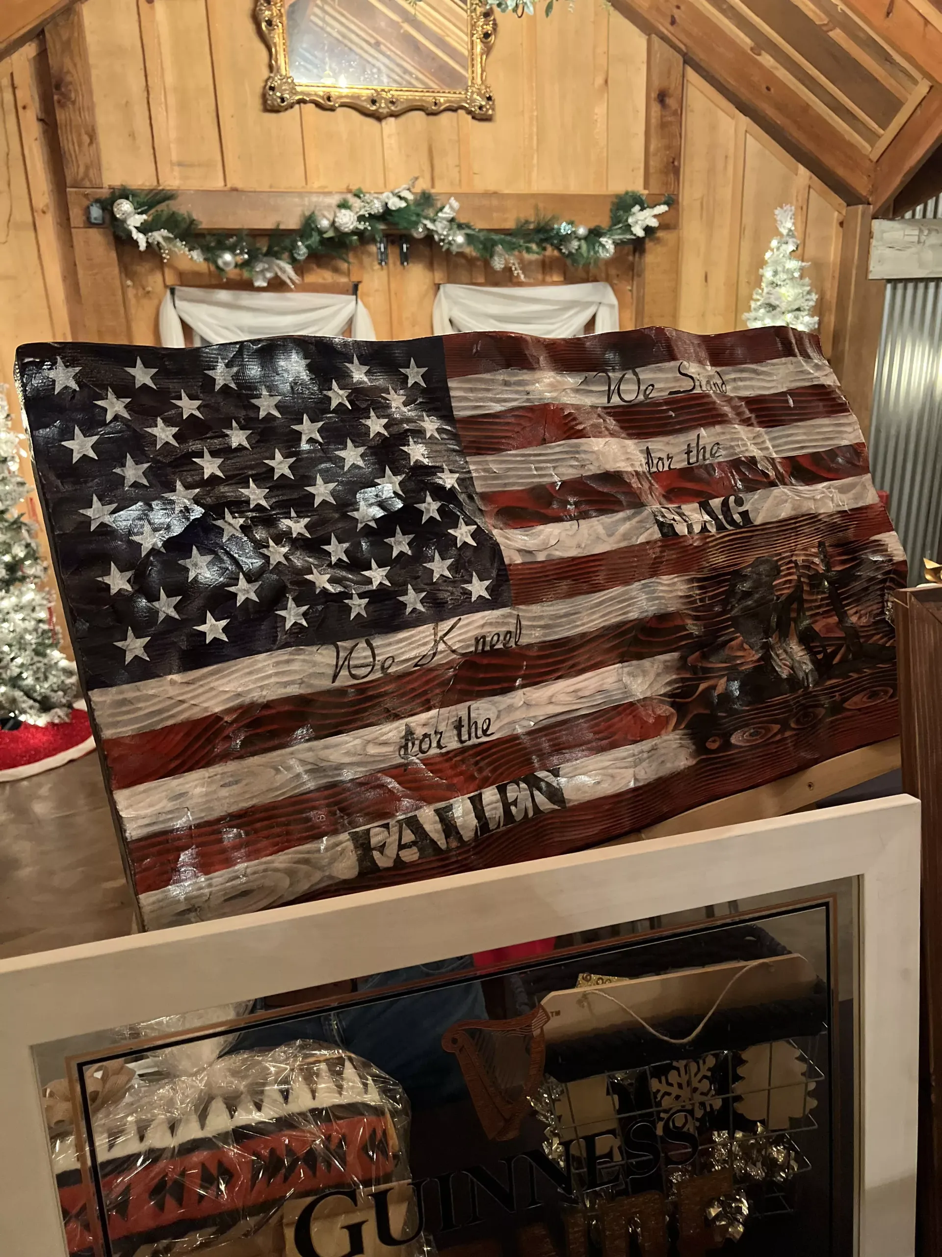 Large distressed American flag artwork in a rustic wood-paneled room with holiday garland nearby