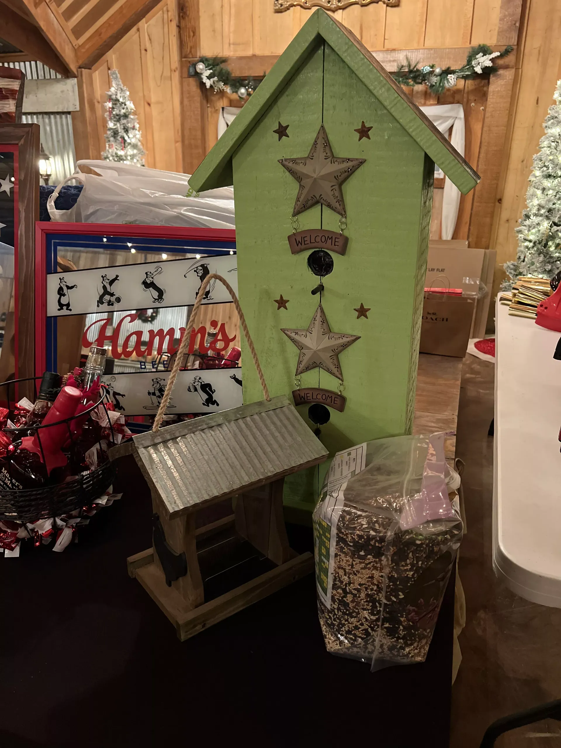 Rustic holiday decor: green star-decorated house, birdhouse, and festive gift bags on a table