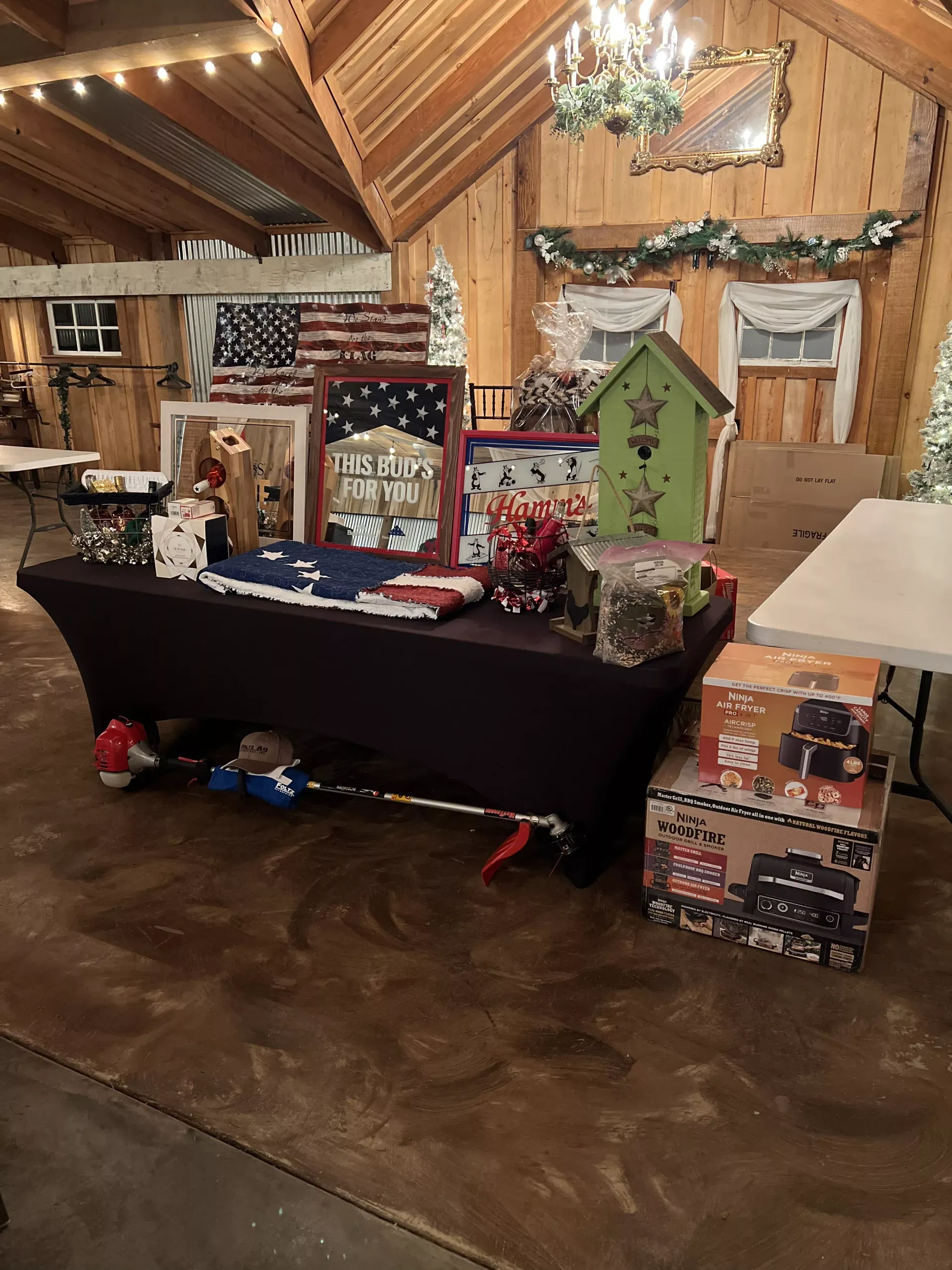 Festive holiday display on a table with crafts, gift boxes, and a small green birdhouse in a wooden hall