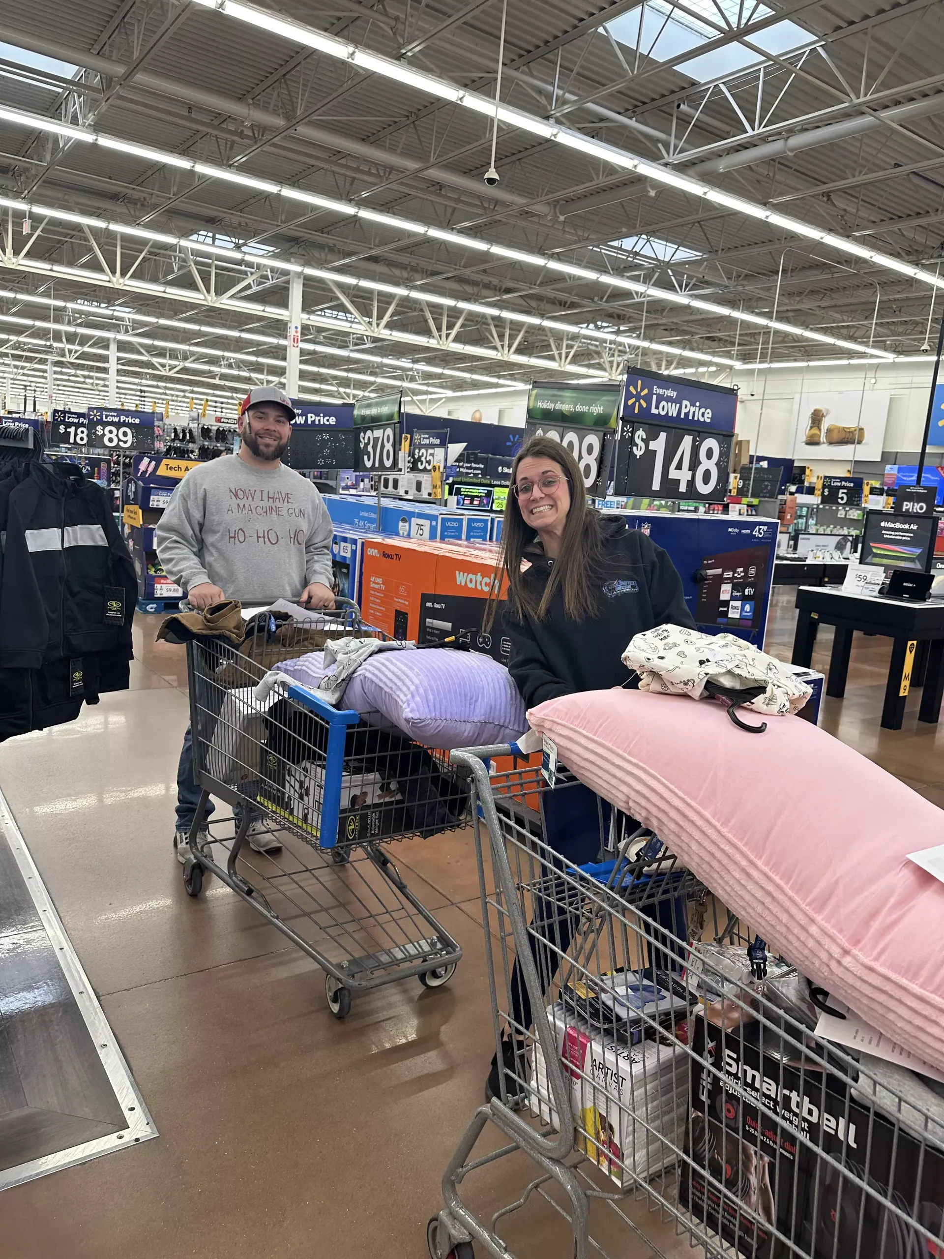 Shoppers with a cart full of pillows and bedding in a store aisle under a $148 sign